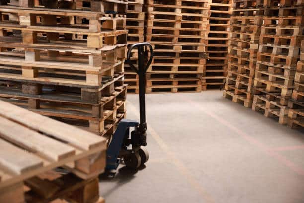 Modern manual forklift with wooden pallets in warehouse, space for text